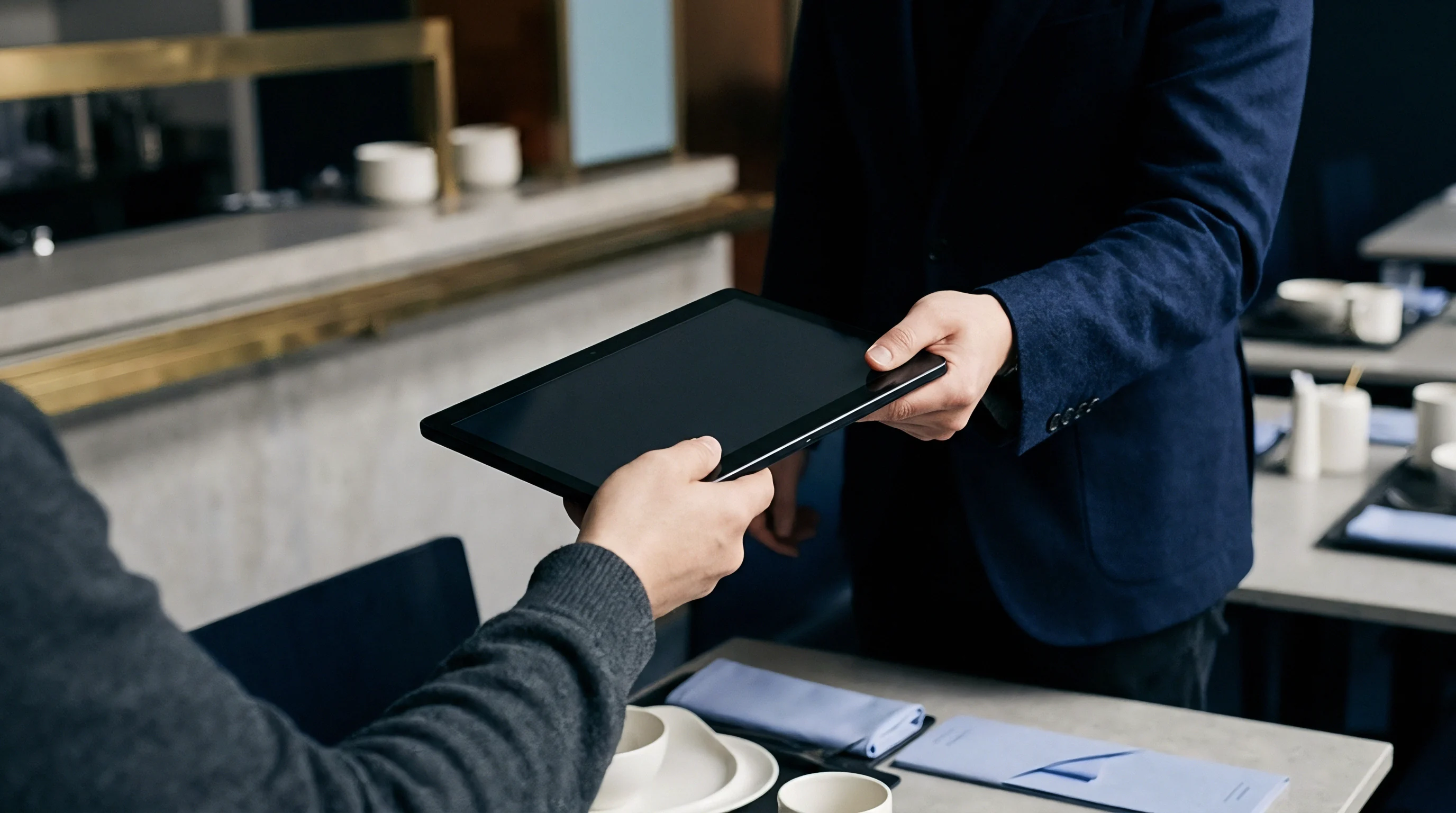 A manufacturing auditor hands a portable electronic tablet across a table during an on site compliance review meeting.