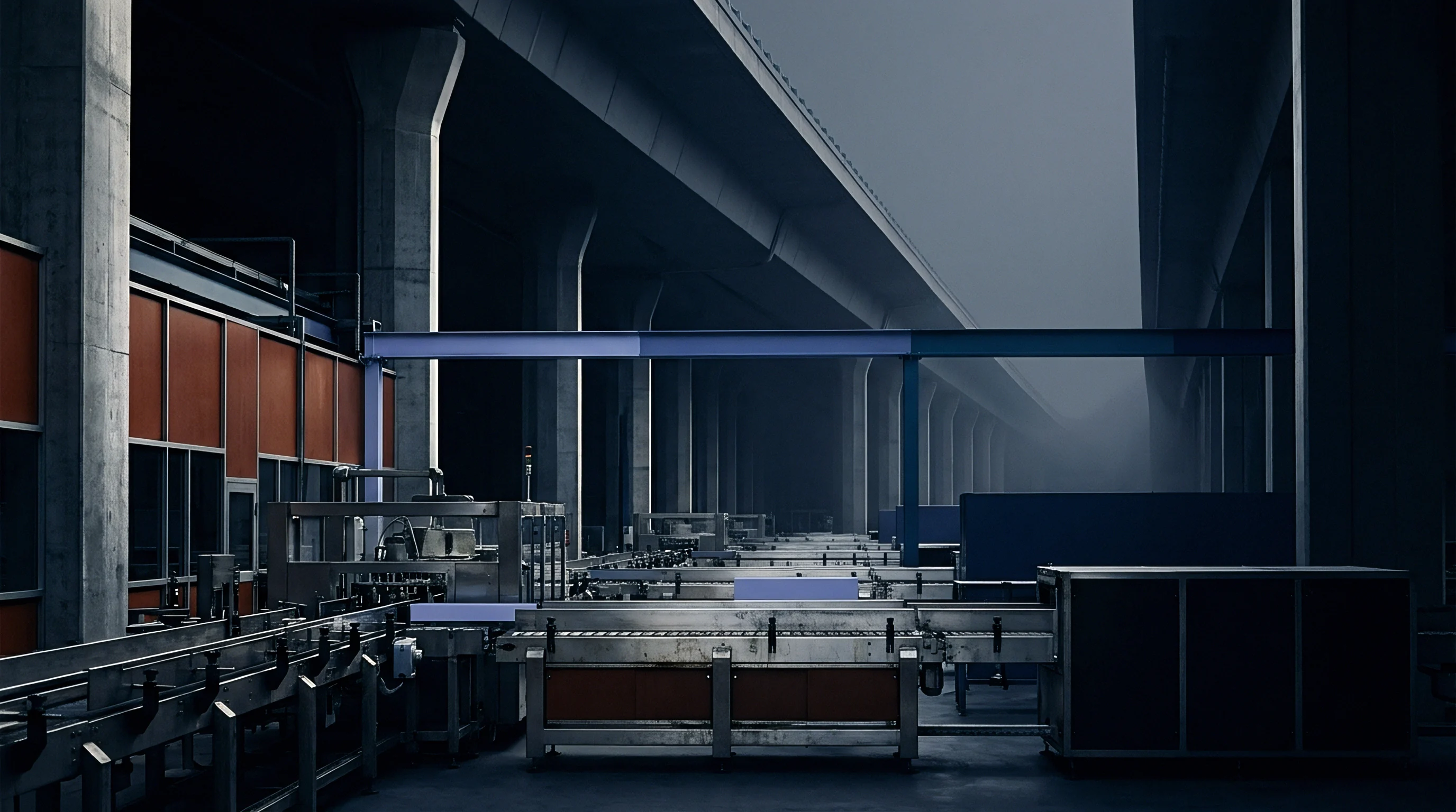 Steel conveyor systems and automated machinery operate inside a vast concrete manufacturing facility built directly beneath an elevated highway overpass.