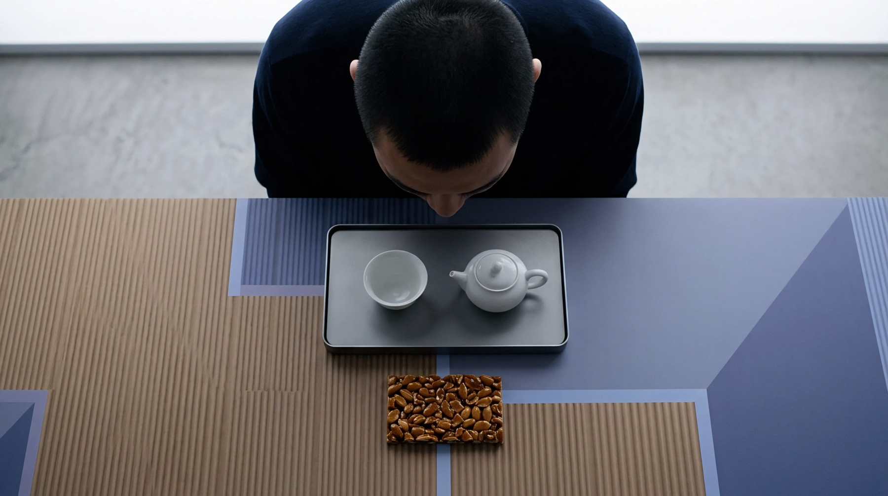A production inspector assesses a ceramic tea set and a confectionery sample on a patterned work surface during quality verification.